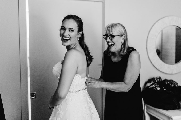 candid moments with mom on wedding day, helping daughter into bride gown