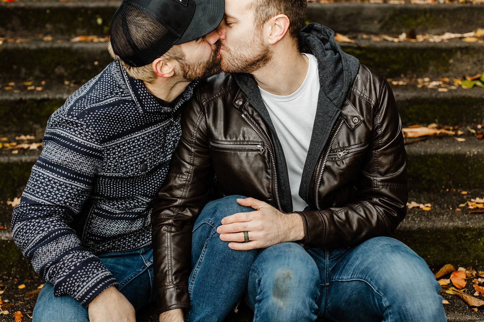couple sitting on cement steps embracing and kissing, one with a dirty knee from kneeling on wet ground after proposal