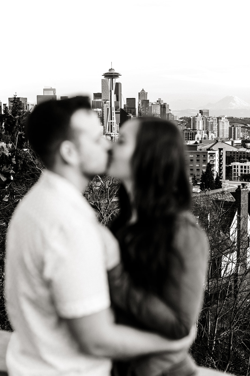 couple kissing with skyline in the background with camera focused on space needle