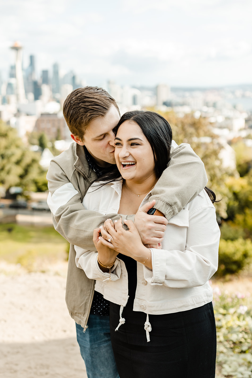 couple of man giving a woman a bear hug and giving her a kiss on the cheek seattle proposal photographer