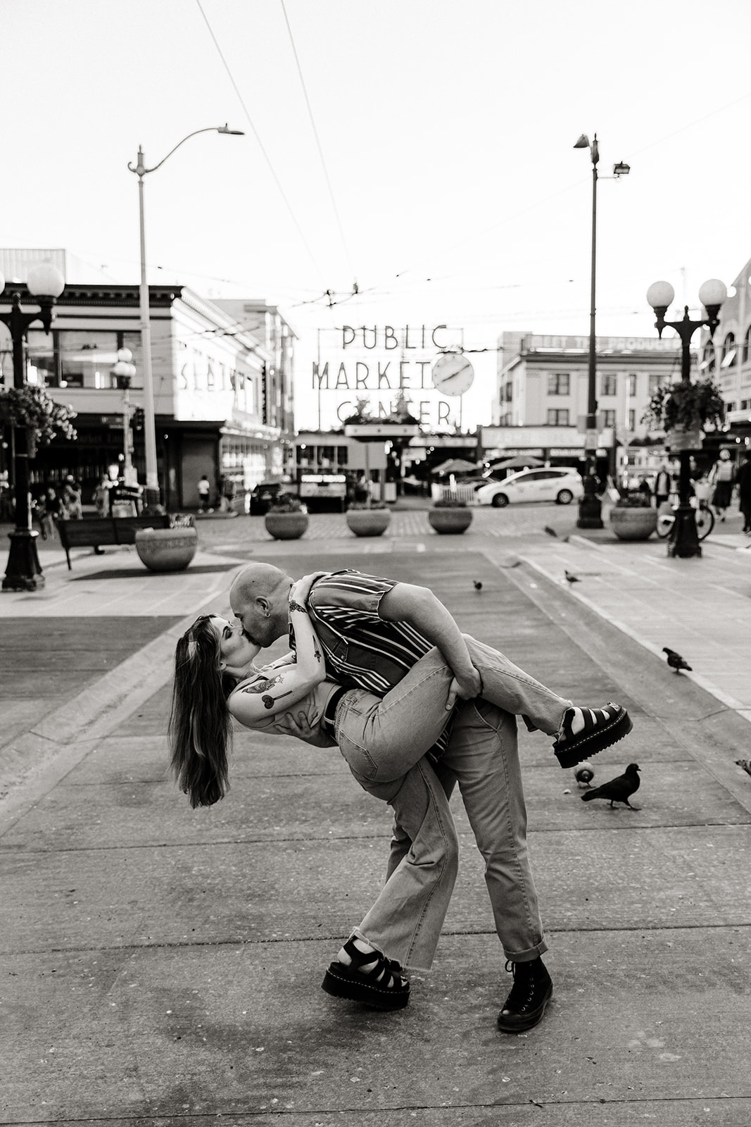 couple dip kiss dancing in the middle of the street in front of pike place sign