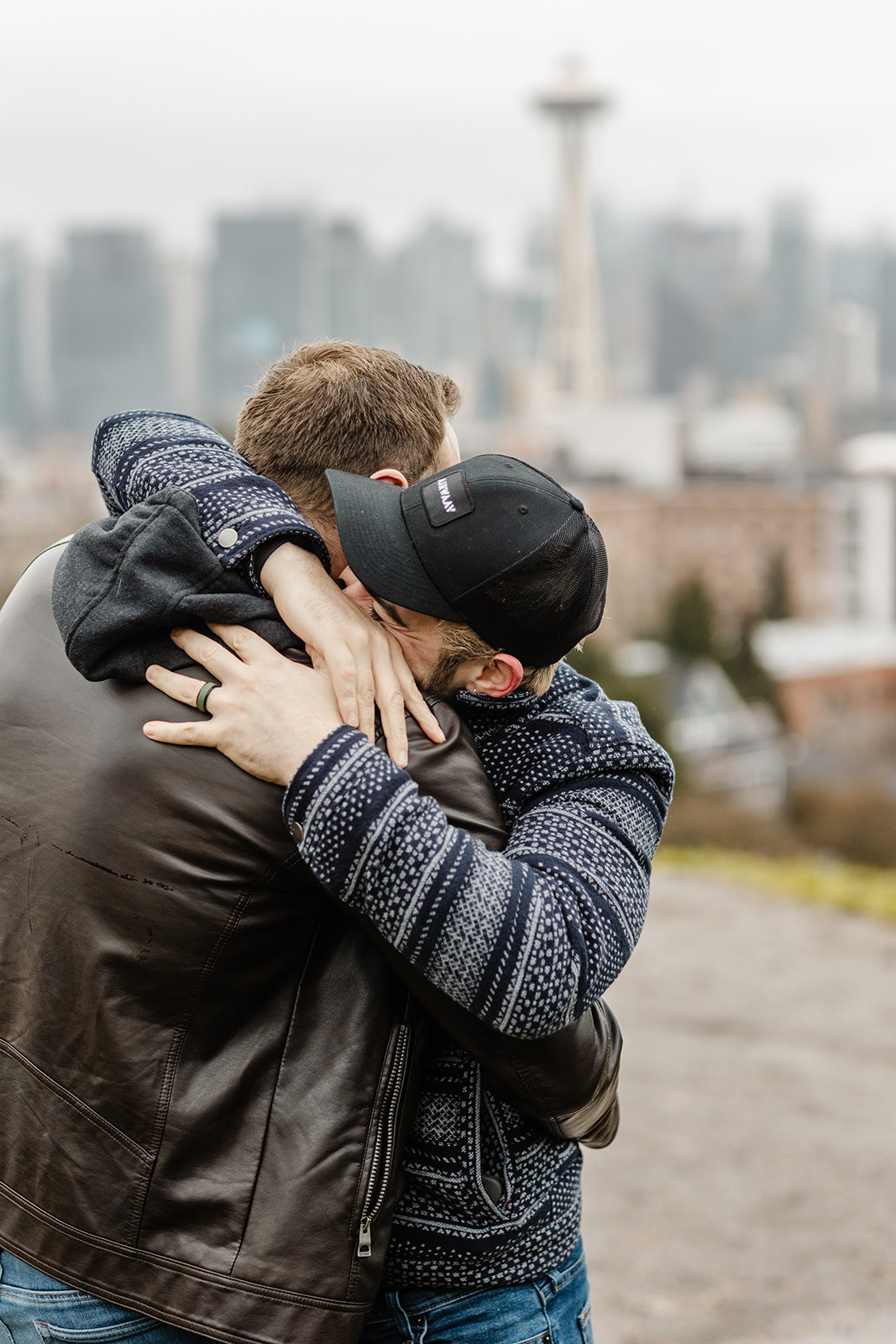 two men embracing after proposal in front of space needle in seattle