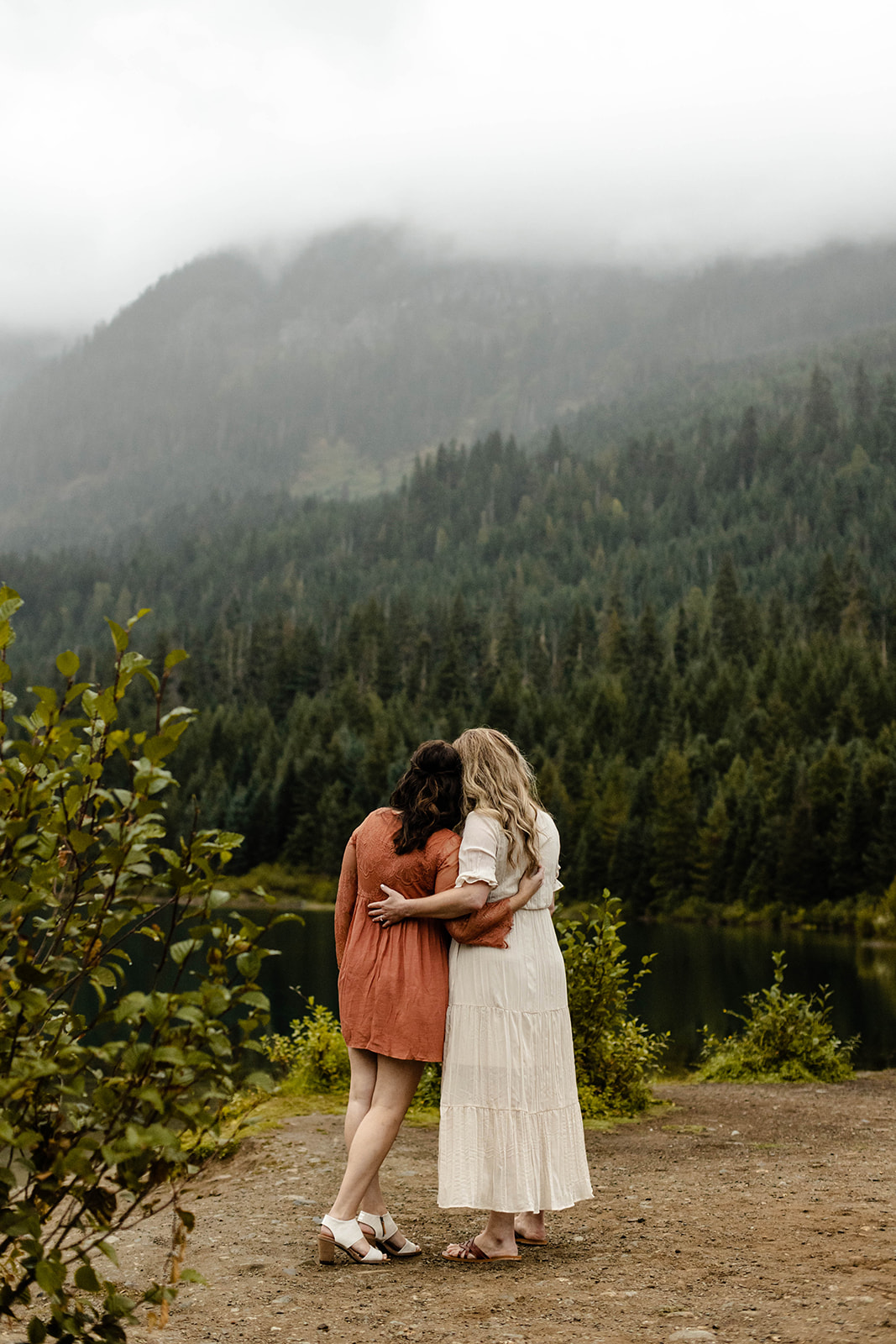 Couple embraces, their backs to the camera, admiring Gold Creek Pond for their fall engagement photos