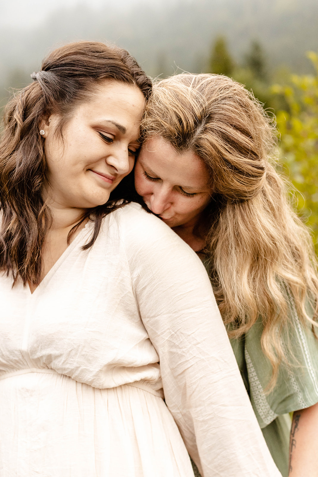 close up of partner leaving a kiss on her fiancee's shoulder