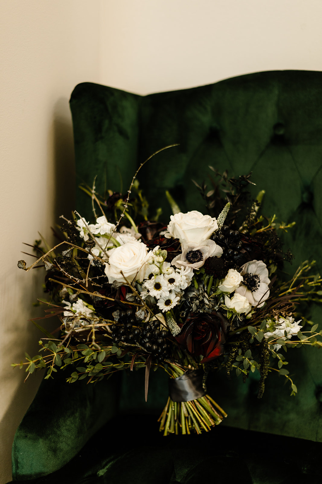 deep green couch with black and white wedding flowers resting on it.