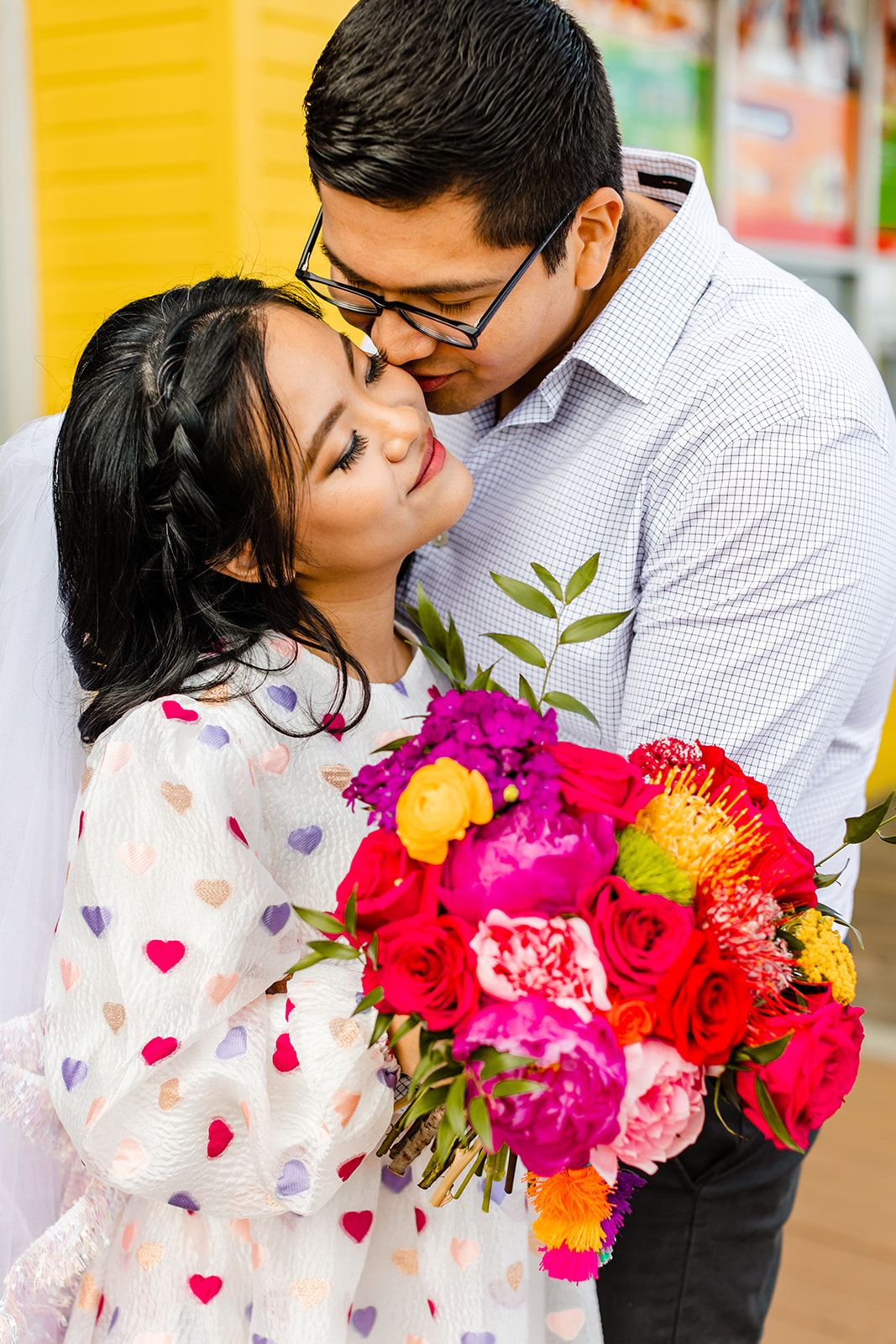 Groom leans down to kiss bride on the cheek. 