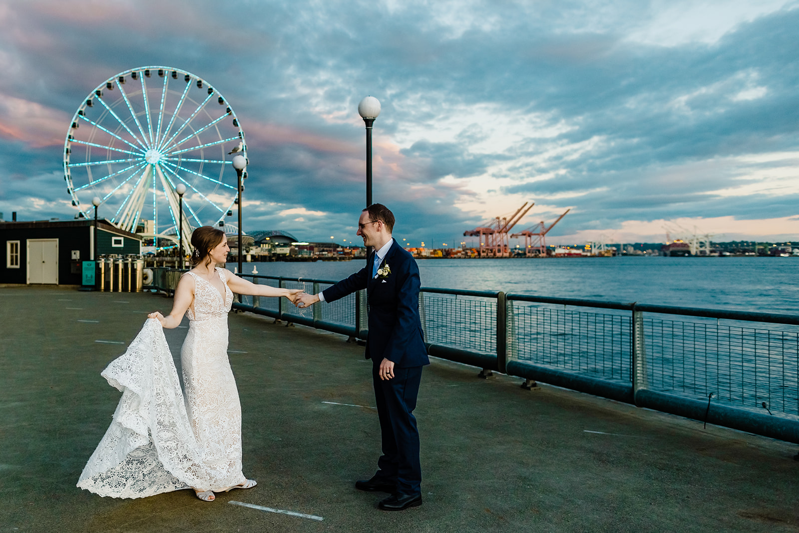 groom twirls bride in front of the ferris wheel.