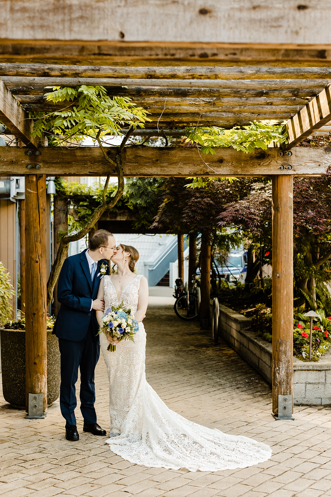 couple kisses under a trellis archway.