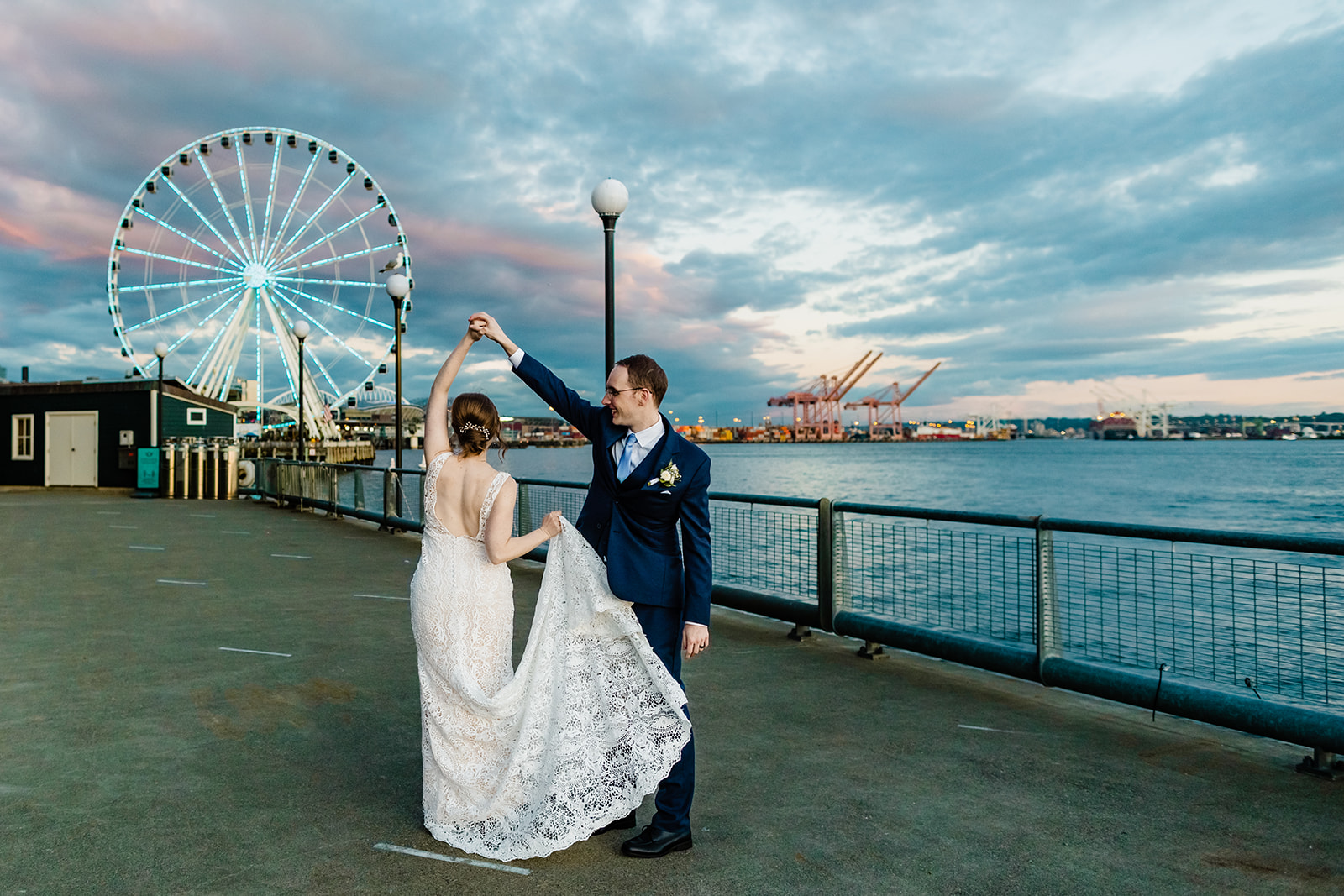 groom twirls bride in front of the ferris wheel.