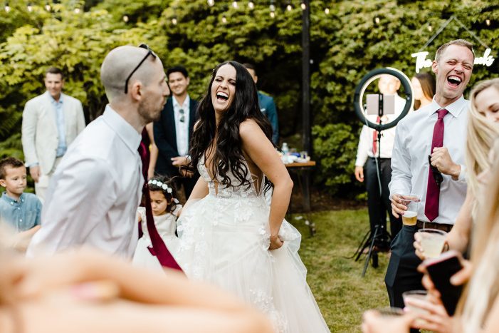 bride laughs while dancing with guests