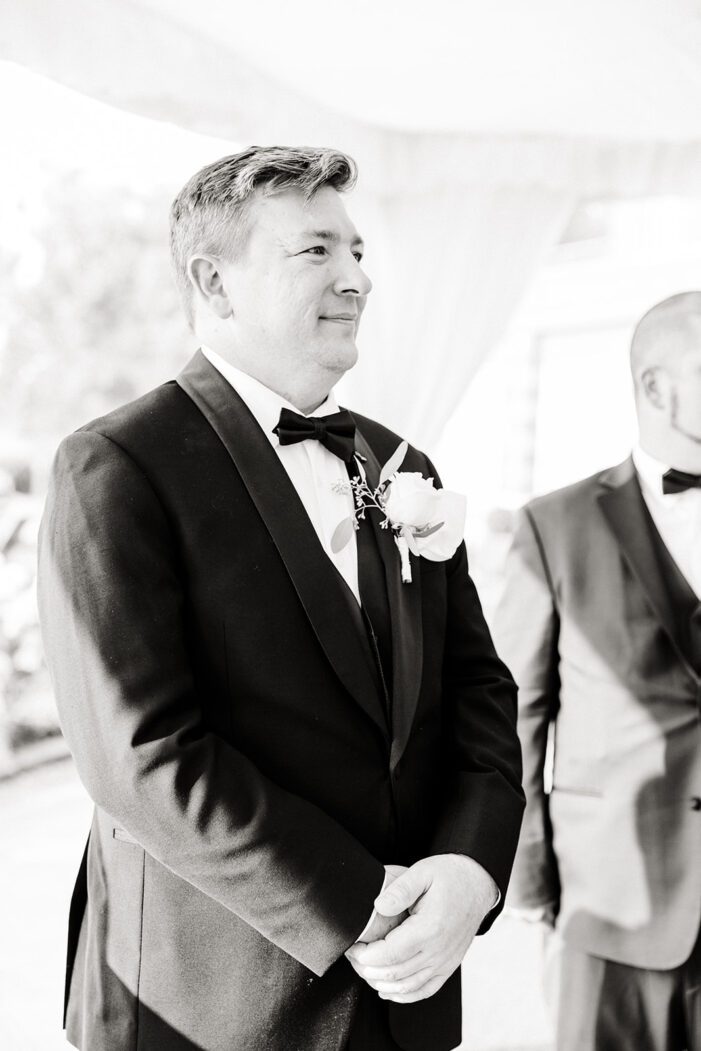 groom looks down aisle at bride