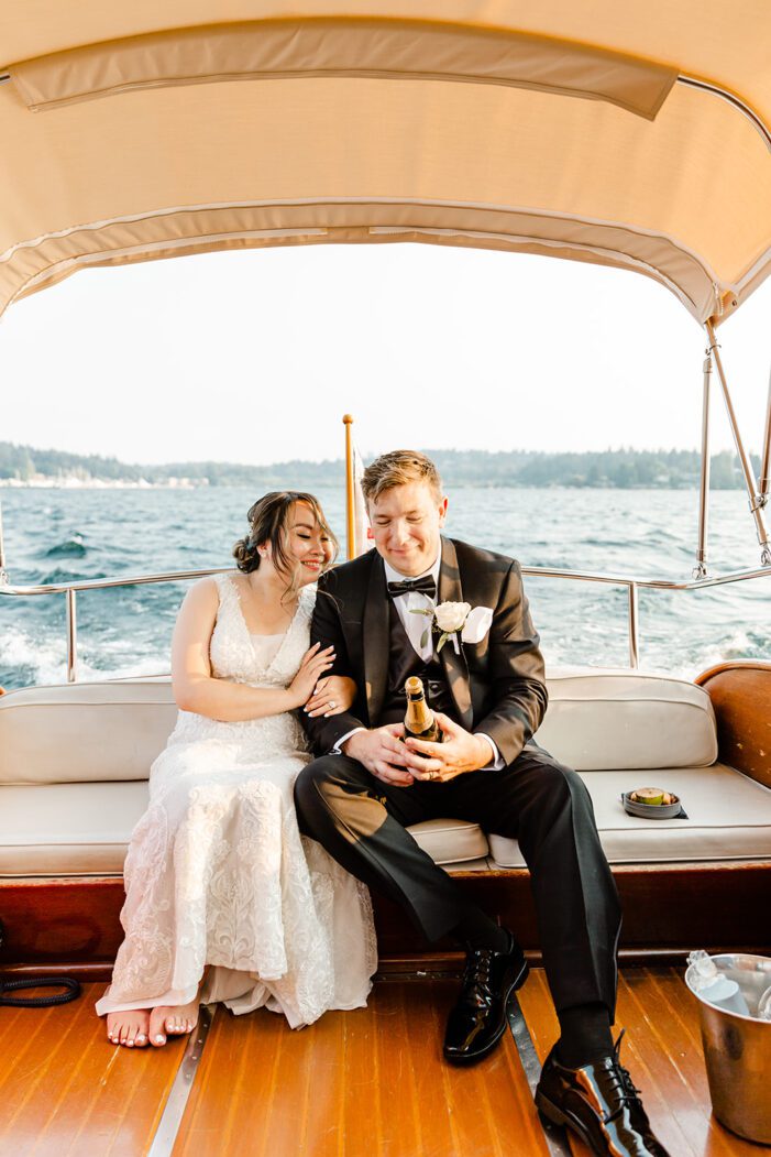 bride and groom snuggle in back of boat during wedding