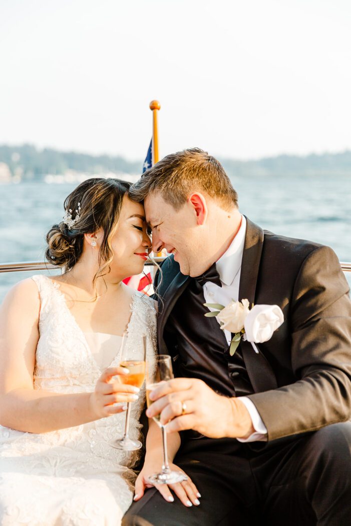 bride and groom hold champagne and snuggle in back of boat
