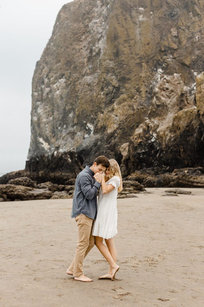 boy and girl hold each other in front of ocean cliffside