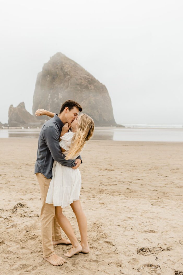 boy and girl hug in front of haystack rock