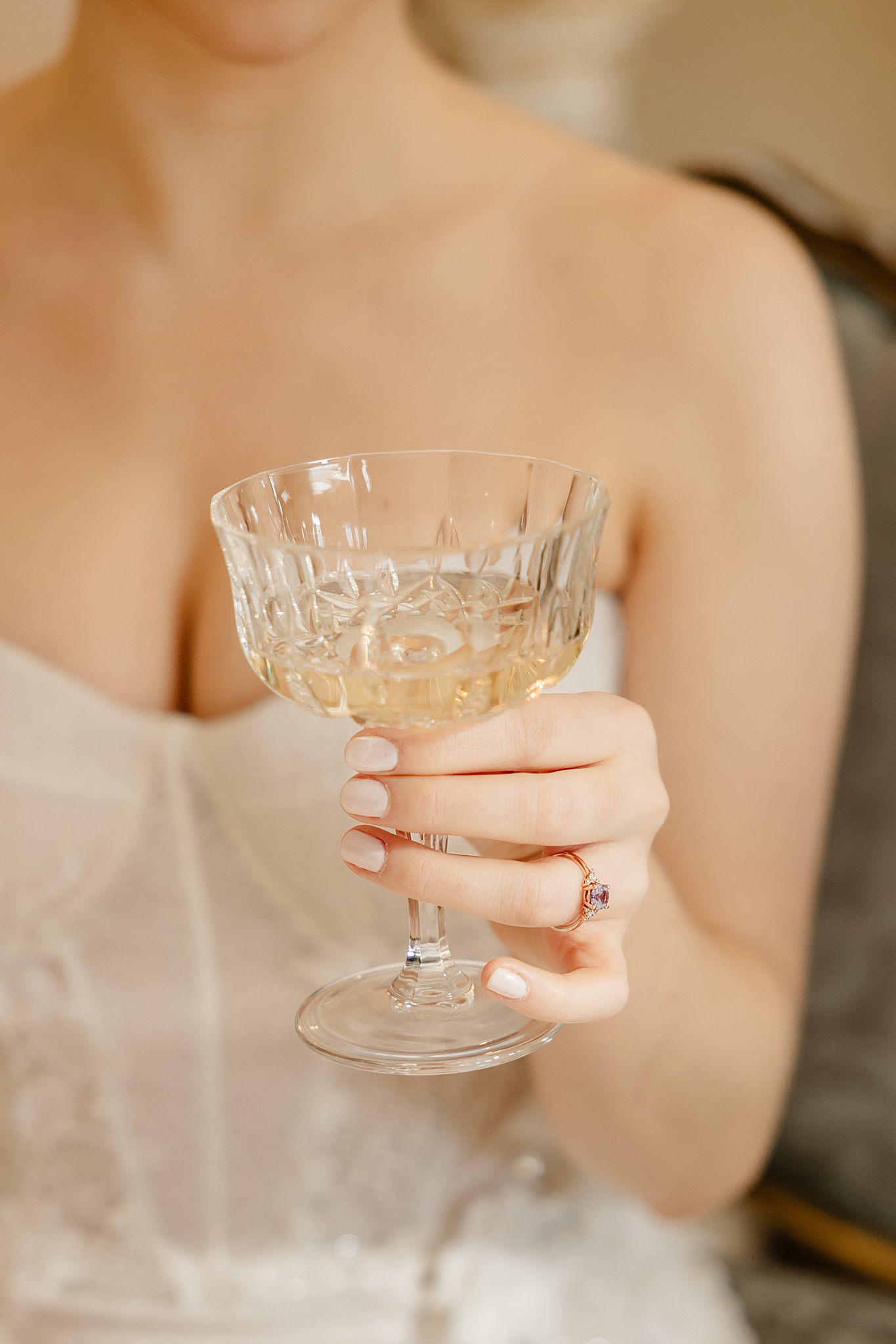 bride with purple engagement ring holding glass of champagne