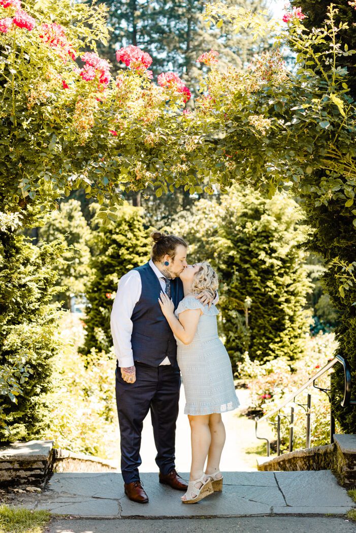 boy and girl kiss in front of greenery