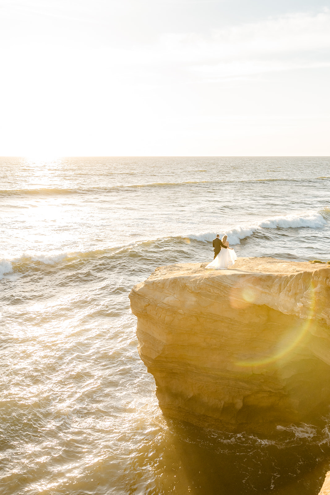 bride and groom stand on the cliff during sunset cliffs elopement