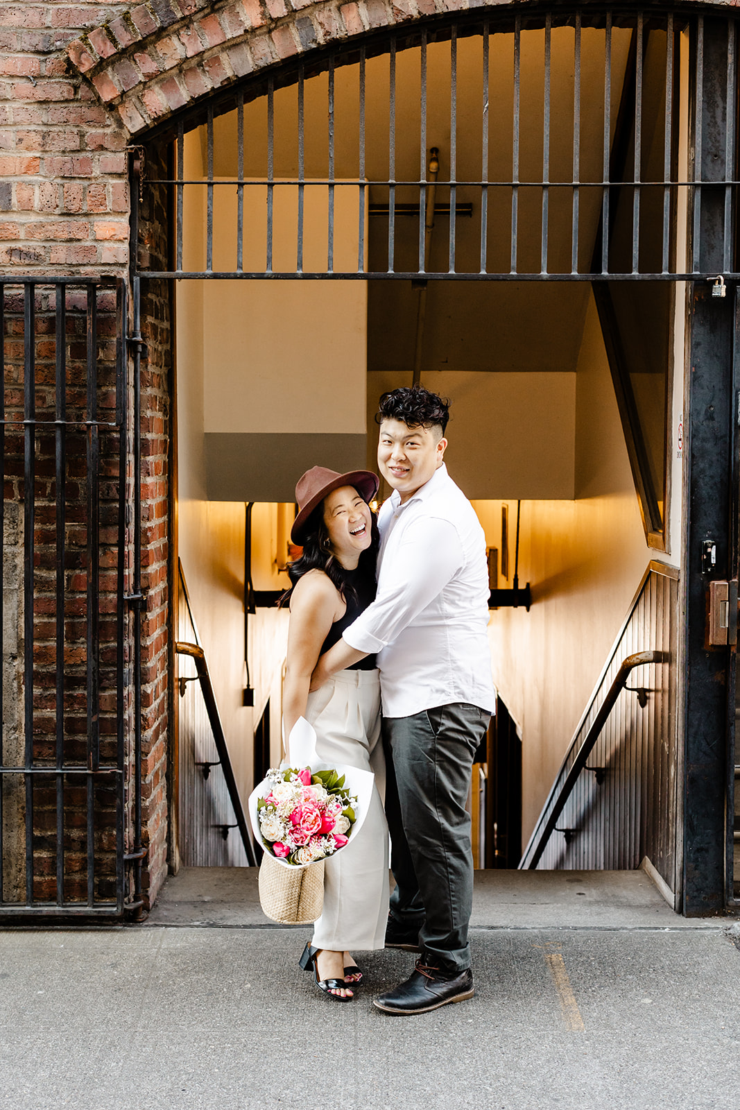 boy and girl look at each other, girl is wearing a hat and holding flowers