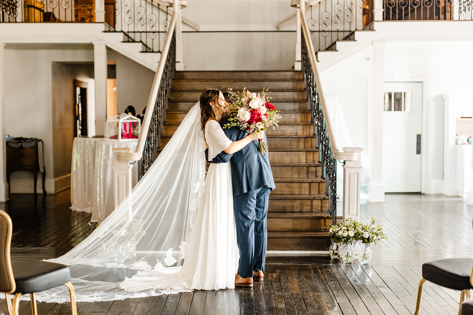 bride and groom hug in front of stairs