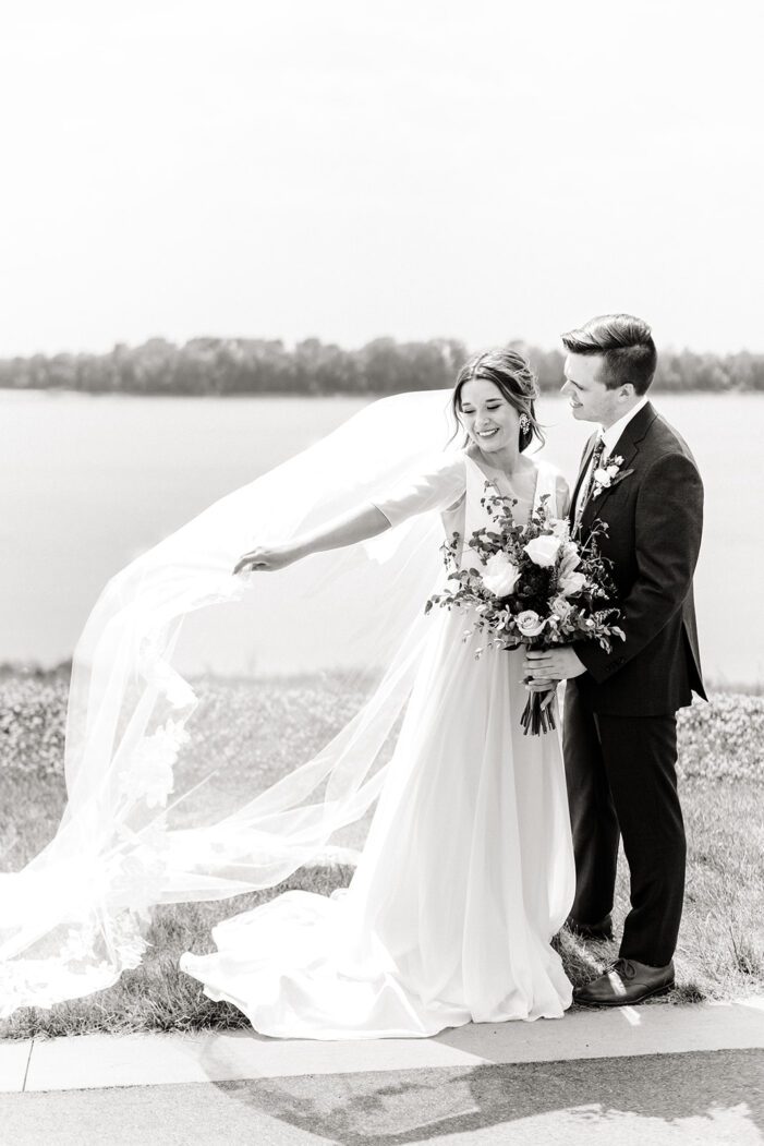 bride and groom face each other as bride holds veil out behind her