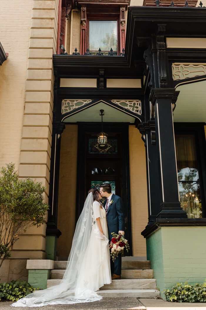 bride and groom stand in front of mansion