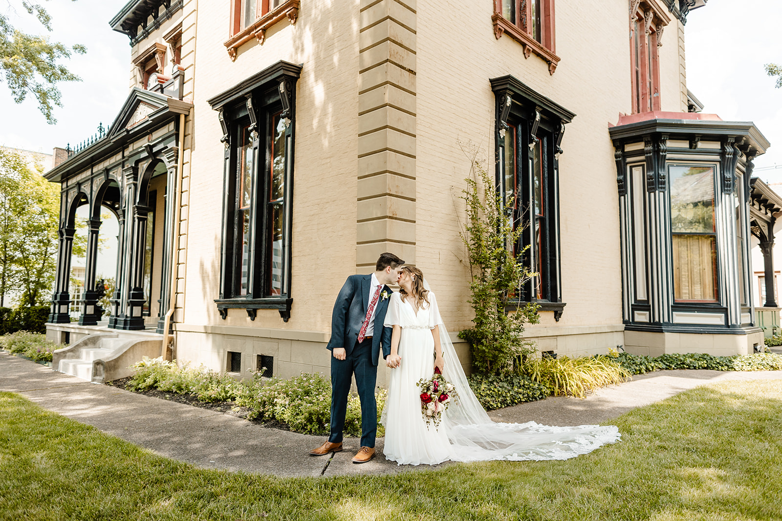 bride and groom stand in front of building during classic wedding photography