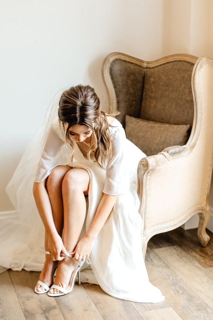 bride bends down and puts on shoes