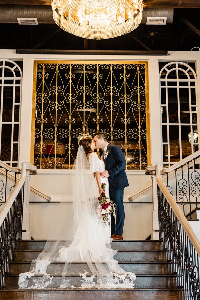 bride and groom kiss at top of stairs