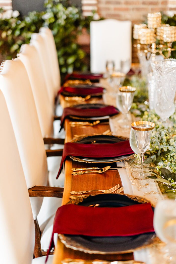 red and gold wedding tablescape with greenery