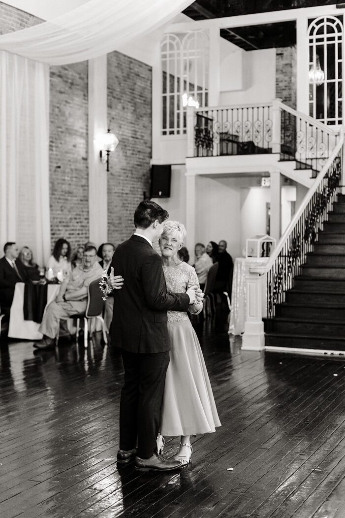 groom dances with mom in front of wedding guests