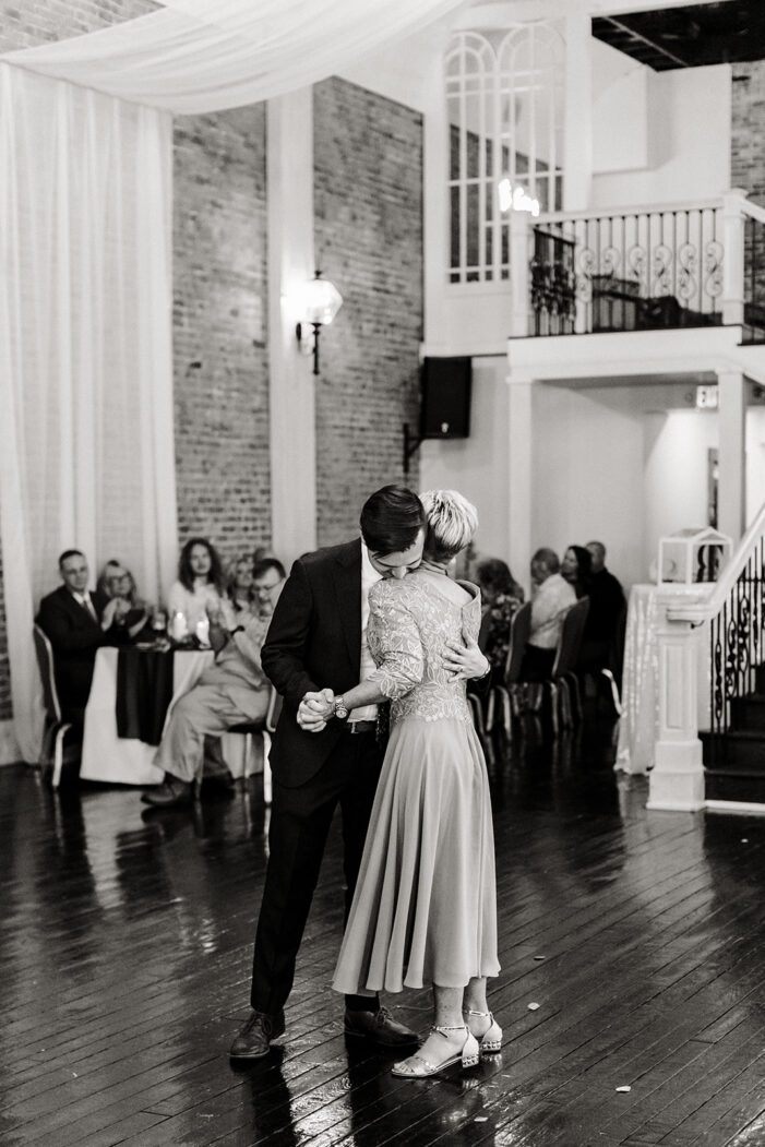 groom dances with mom in front of wedding guests