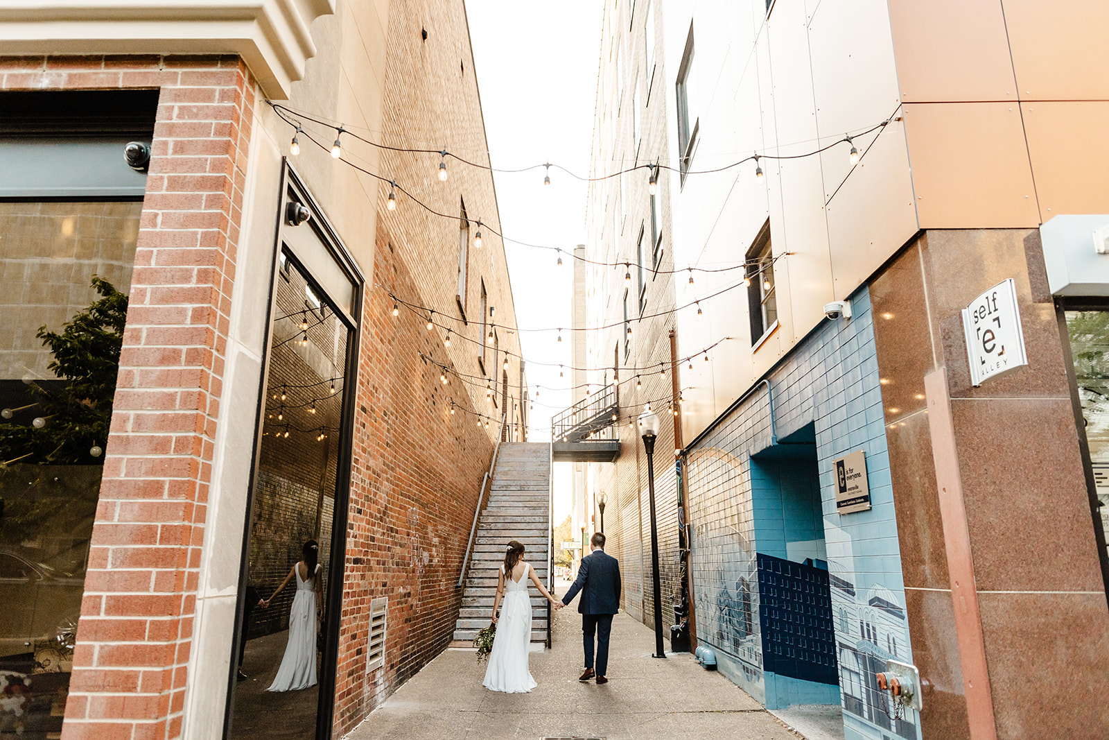 bride and groom walk down a bricked alley way together