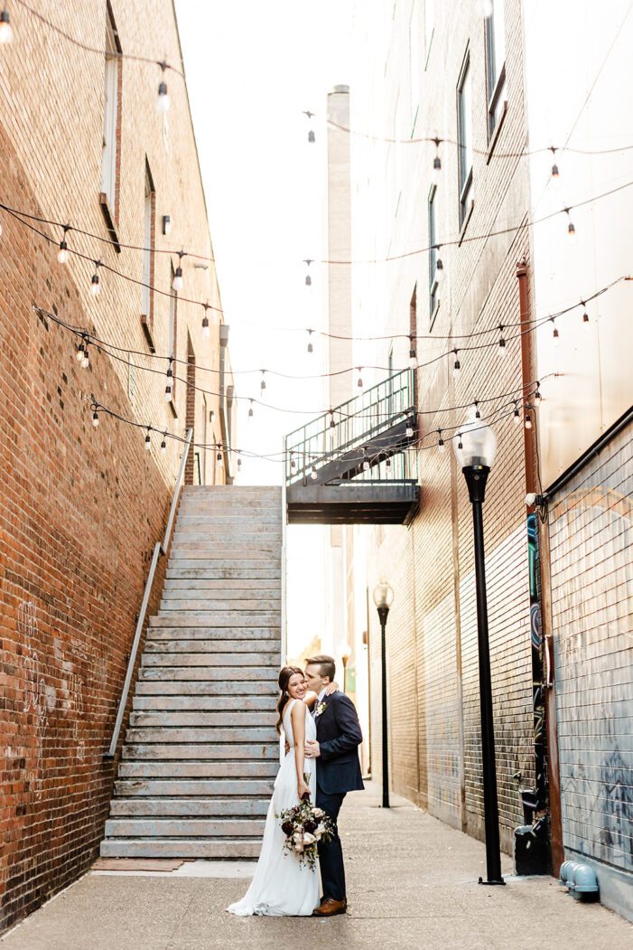 bride and groom walk down a bricked alley way together