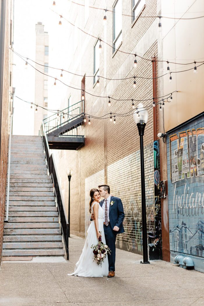 bride and groom walk down a bricked alley way together