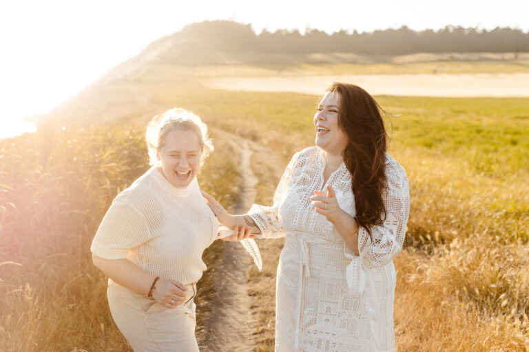 two brides stand in a field laughing together Whidbey Island Engagement