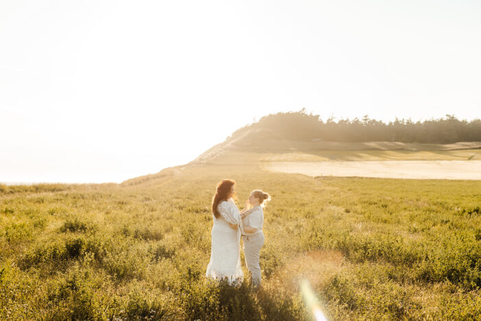 two brides walk through golden field during Whidbey Island Engagement