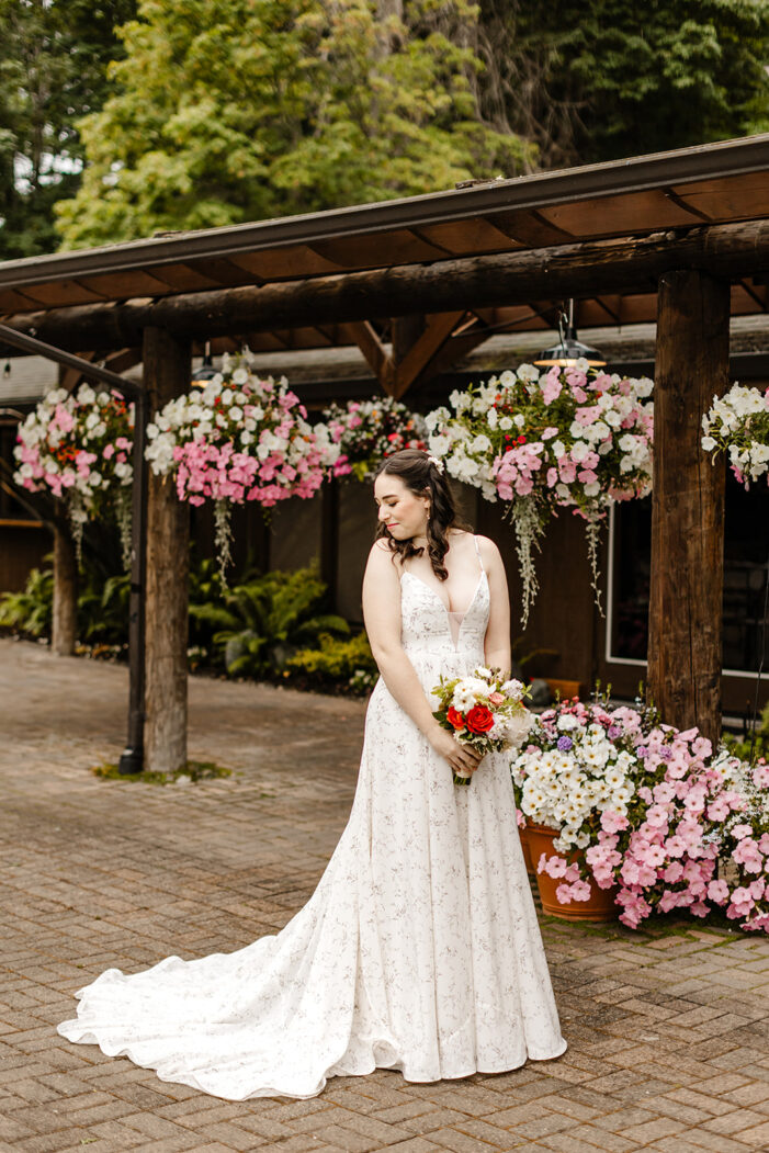 bride poses in front of hanging flower baskets