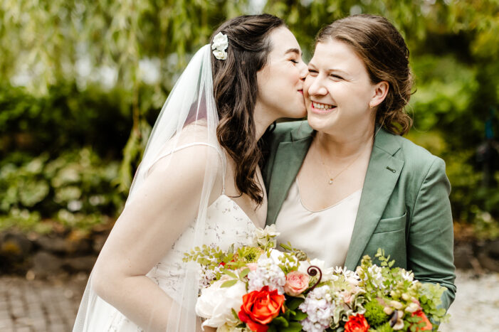 one bride kisses another bride on her cheek