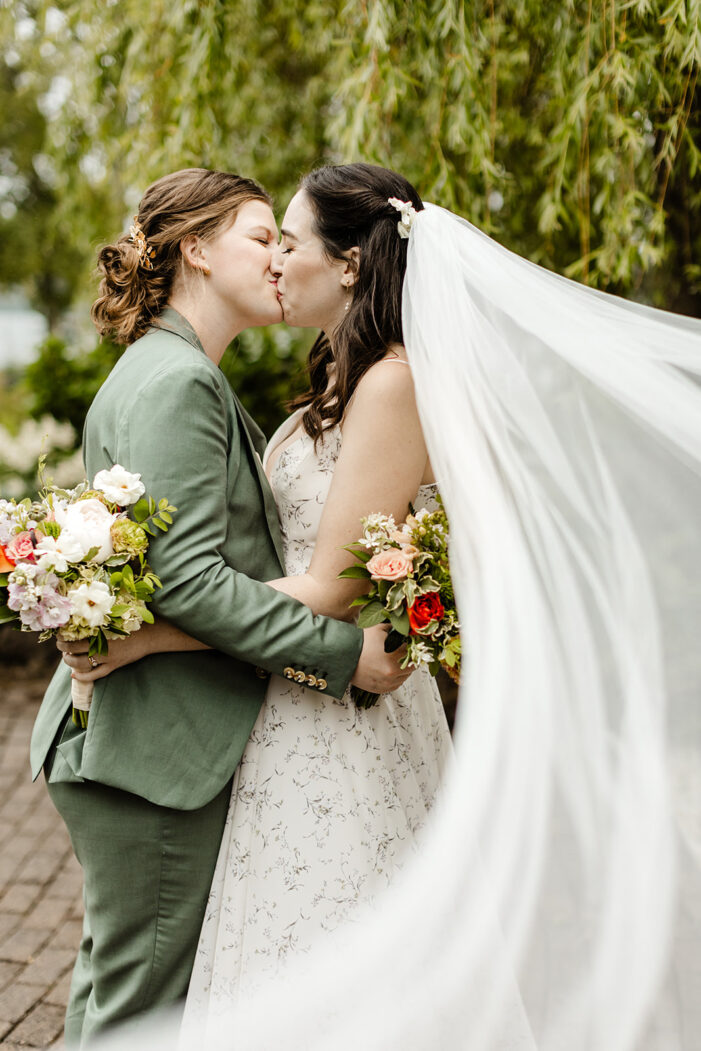 two brides kiss with veil trailing behind