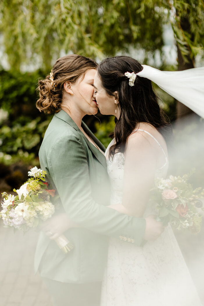 two brides kiss with veil 