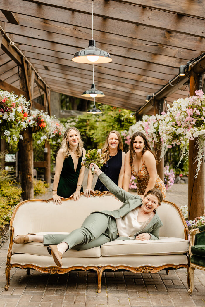 bride lays on couch with bridal party behind her
