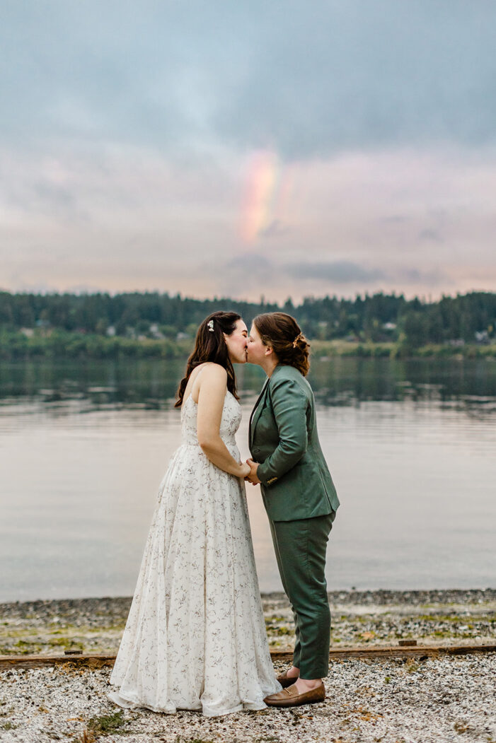 brides lean in and kiss standing on the beach during wedding
