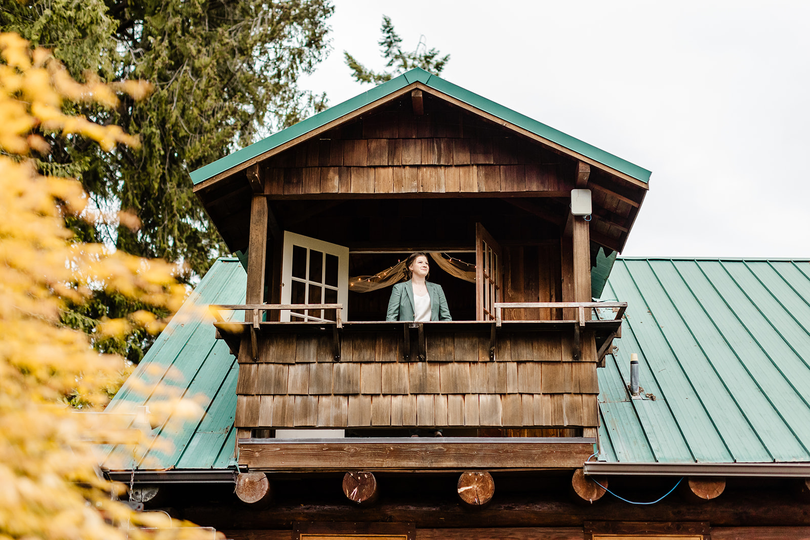 bride in green suit stands on building