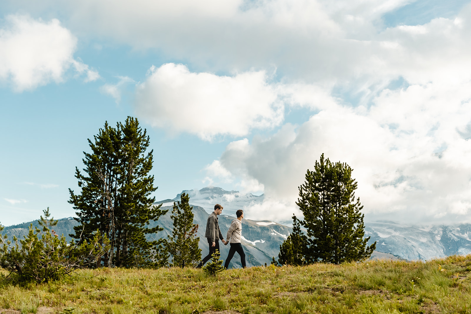 two boys walk across a hill in a field during mt rainier engagement session