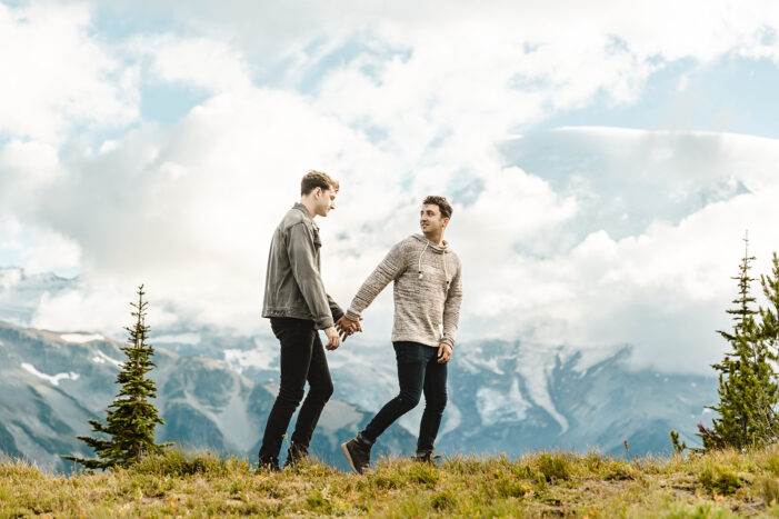 two boys walk across a hill in a field during mt rainier engagement session