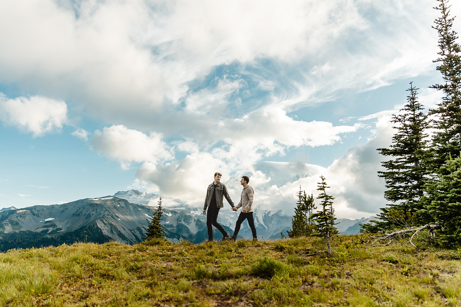 two boys walk across a hill in a field during mt rainier engagement session