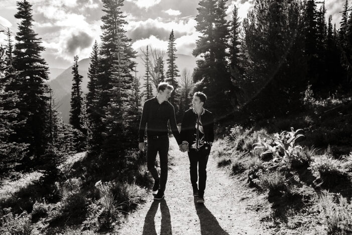 two boys walk down a path through the trees during engagement session
