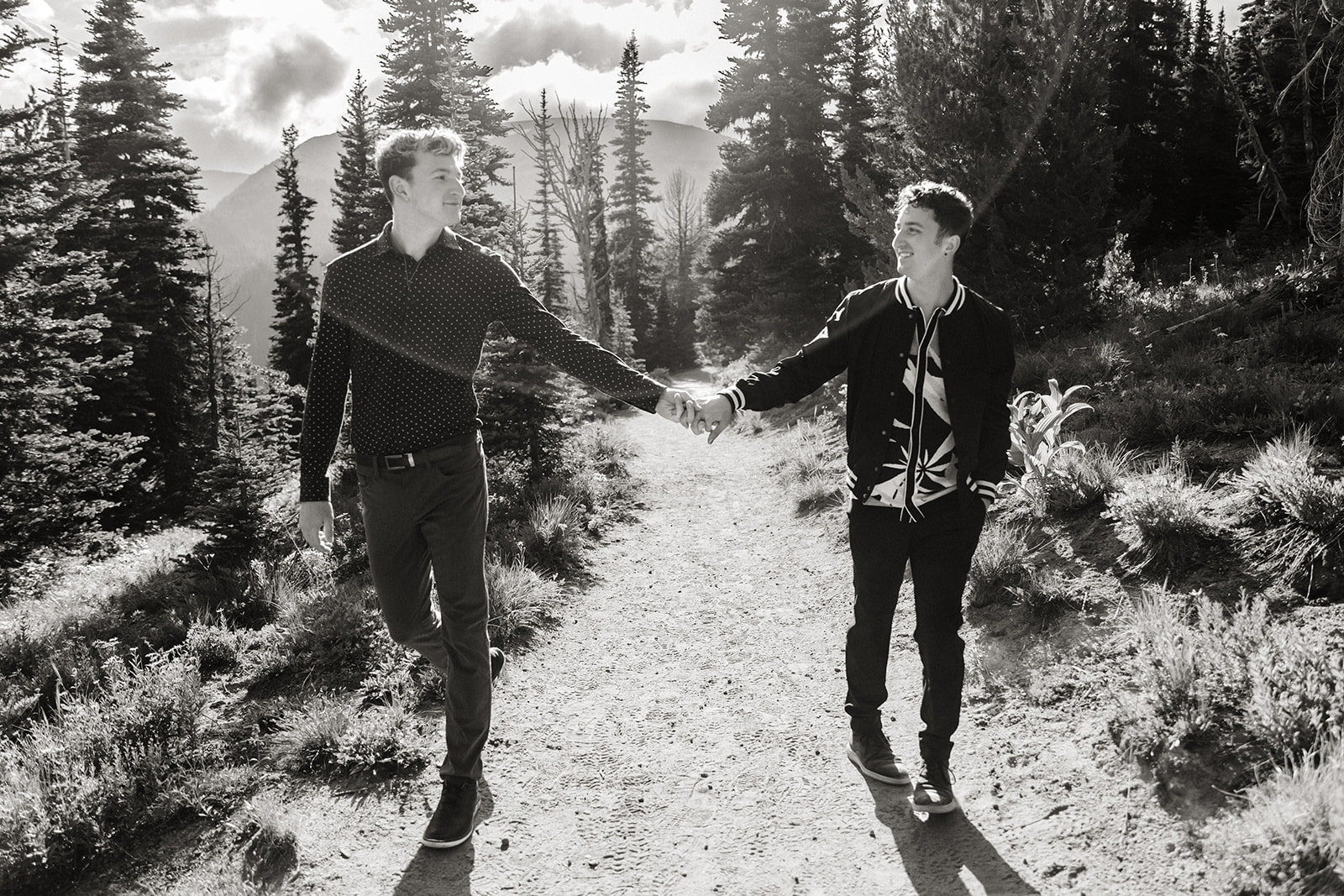 two boys hold hands and walk through the trees during mountain engagement session
