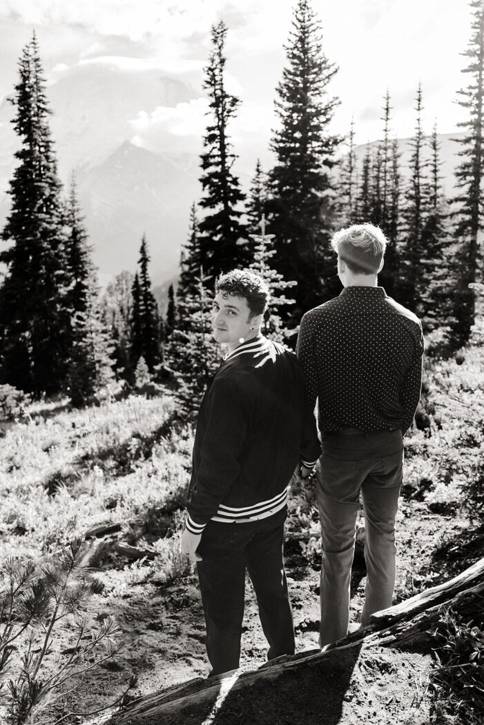 boy looks over his shoulder as he talks through a field with another boy